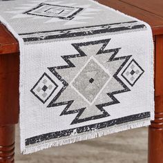 a table with a white and black runner on it's side, next to a wooden table