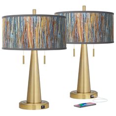 two lamps that are next to each other with a phone on the table in front of them