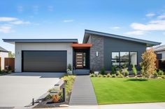 a modern home with grass and landscaping in the front yard