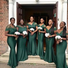 a group of women standing next to each other in front of a door wearing green dresses