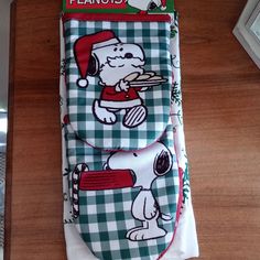 a pair of oven mitts with snoopy on them sitting on top of a wooden table