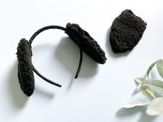 two pieces of black hair are laying on a white surface next to flowers and leaves