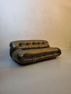 a brown leather couch sitting on top of a white floor next to a wall and lamp