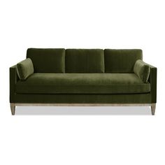 a green velvet couch with wooden legs and pillows on the back, against a white background