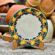 a colorful plate sitting on top of a table next to potted plants and pottery