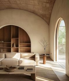 a living room filled with furniture next to an arched window and bookshelf on the wall