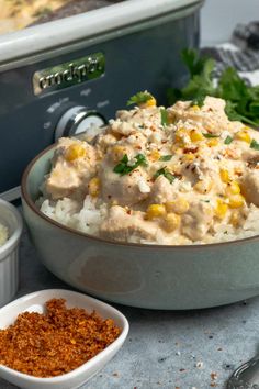 a bowl filled with rice, corn and seasoning next to other dishes