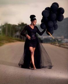 a woman in a black dress holding balloons