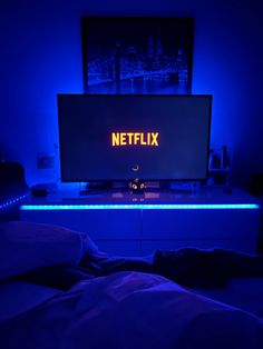 a television sitting on top of a white dresser next to a neon sign that reads netflix