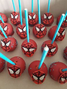 there are many cake pops with spiderman faces on them and blue sticks sticking out of them