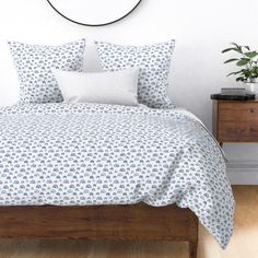 a bed with blue and white bedspread next to a wooden dresser in a bedroom