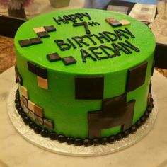 a green birthday cake with the words happy 7th birthday written on it in black letters