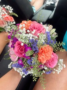 a bouquet of flowers is sitting in the back seat of a car with someone's legs