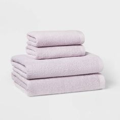 three towels stacked on top of each other in lavender colors, one folded and the other rolled up