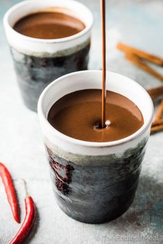 two cups filled with hot chocolate and cinnamon sticks