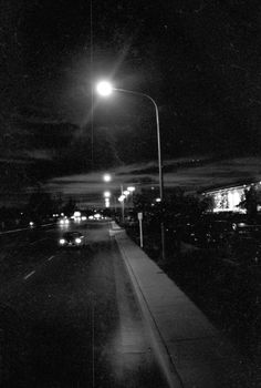 a black and white photo of a street at night