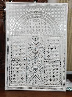 an intricately designed white paper cutting board on a wooden table next to a chair