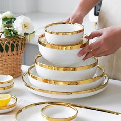 a stack of white and gold dishes on a table