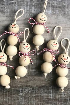 six snowman ornaments hanging from string on wooden table with red and white twine