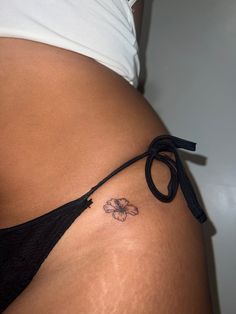 a woman's stomach with a flower tattoo on the side and a black string attached to it