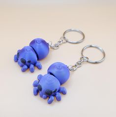 two blue plastic octopus keychains on a white surface with one holding the other's head