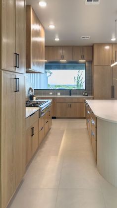 an empty kitchen with wooden cabinets and white counter tops, along with a large window