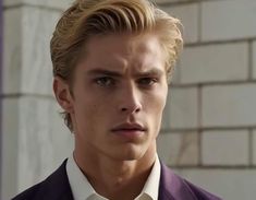 a young man with blonde hair wearing a suit and tie in front of a brick wall