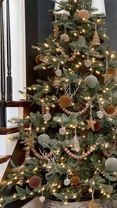 a christmas tree with lights and ornaments in a basket on the floor next to stairs