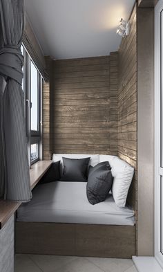 a small room with a bed, window and wooden paneling on the wall behind it