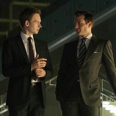 two men in suits are standing outside at night