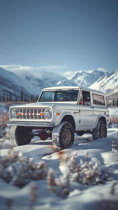 A white vintage Ford Bronco stands proudly in a snowy landscape, its tires covered in fresh snow. The backdrop features a serene mountain range, with the soft glow of sunlight casting a tranquil ambiance over the winter scene. Red Bronco, Vintage Ford Bronco, White Bronco, Broncos Wallpaper, Old Ford Bronco, Old Bronco, Landscape With Mountains, Early Bronco