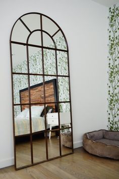 a large mirror sitting on top of a hard wood floor next to a dog bed