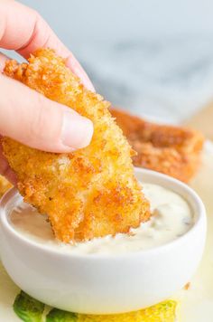 a person dipping something into a small white bowl