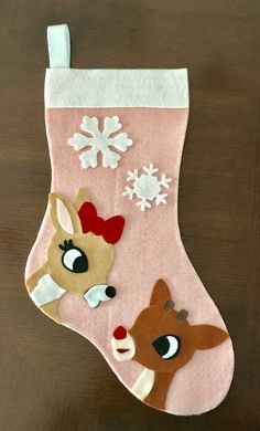 a pink christmas stocking with reindeer and snowflakes hanging from it's side