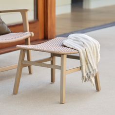 a chair with a blanket on it sitting in front of a wooden bench and door