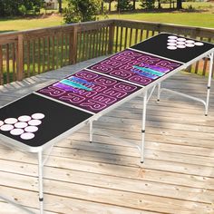 a long table on a wooden deck with purple and white designs painted on it's sides