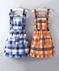 two children's dresses hanging on a clothes rack, one in orange and the other in blue