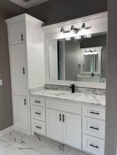 a large bathroom with marble counter tops and white cabinetry, along with two sinks