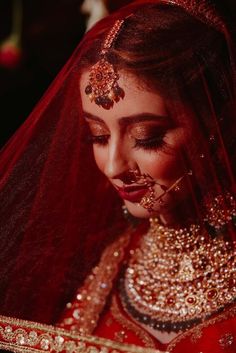 a woman wearing a red and gold bridal outfit