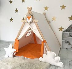 a child's teepee tent with stars on the wall behind it and an orange bed