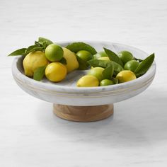 a bowl filled with lemons and limes on top of a marble countertop