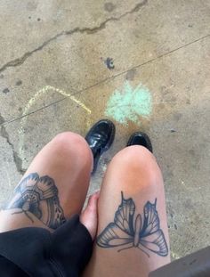 a woman's legs with tattoos on them sitting next to another person wearing black shoes