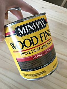 a person holding a can of wood finishing stain