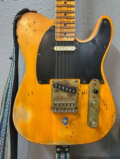 an old yellow electric guitar hanging on the wall