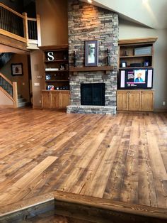 an empty living room with wood floors and stone fireplace in the center, surrounded by stairs