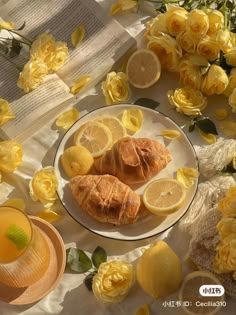 a plate with lemons and croissants on it next to yellow flowers