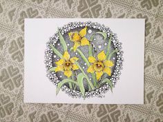 yellow daffodils in a circle on a white card with lace doily