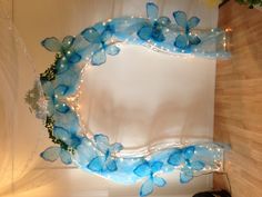 an arch made out of blue glass with fairy lights on it and some flowers in the middle