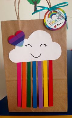 a brown paper bag with rainbow sticks sticking out of it's side and a happy cloud on top