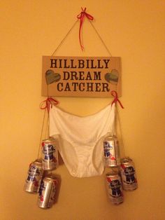 there is a sign that says hillbilly dream catcher with six cans hanging from it